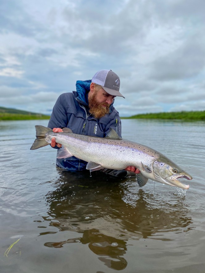 A fisher holding a large atlantic salmon.